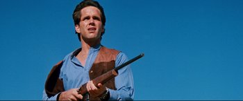 Movie still from “Razorback” (1984), directed by Russell Mulcahy – A man holding a rifle in his hands; Close Up shot, Low angle