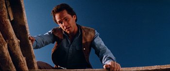 Movie still from “Razorback” (1984), directed by Russell Mulcahy – A man wearing a leather vest leaning against a wall; Close Up shot, Low angle