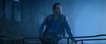 Movie still from “Razorback” (1984), directed by Russell Mulcahy – A man in a blue shirt and a brown vest; Medium shot, Low angle