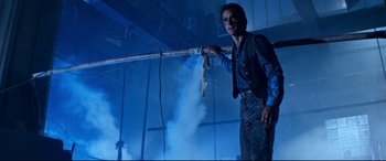 Movie still from “Razorback” (1984), directed by Russell Mulcahy – A man holding onto a rope with smoke coming out of it; Medium shot, Low angle