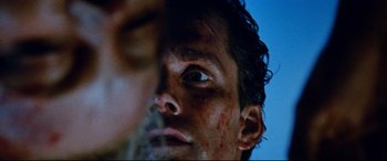 Movie still from “Razorback” (1984), directed by Russell Mulcahy – A man's face covered in blood; Extreme Close Up shot, Over the shoulder angle