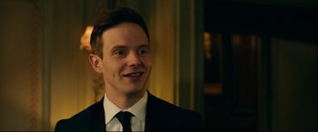 Movie still from “Ready or Not” (2019), directed by Matt Bettinelli-Olpin – A man in a suit and tie smiling for the camera; Close Up shot, Over the shoulder angle
