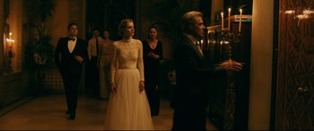 Movie still from “Ready or Not” (2019), directed by Matt Bettinelli-Olpin – A woman in a white dress standing in front of a man; Wide shot, Over the shoulder angle