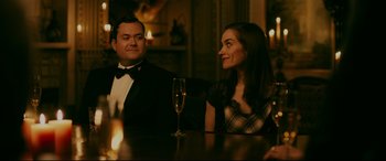 Movie still from “Ready or Not” (2019), directed by Matt Bettinelli-Olpin – A man and a woman sitting at a table with a glass of champagne; Medium shot, Over the shoulder angle