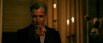 Movie still from “Ready or Not” (2019), directed by Matt Bettinelli-Olpin – A man in a suit and tie pointing at the camera; Close Up shot, Over the shoulder angle