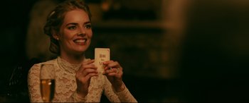 Movie still from “Ready or Not” (2019), directed by Matt Bettinelli-Olpin – A woman is holding up a card and smiling for the camera; Close Up shot, Over the shoulder angle