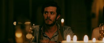 Movie still from “Ready or Not” (2019), directed by Matt Bettinelli-Olpin – A man sitting in front of a table with candles in the background; Close Up shot, Over the shoulder angle