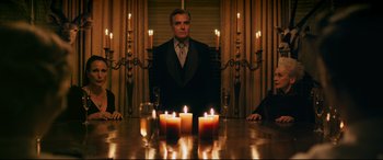 Movie still from “Ready or Not” (2019), directed by Matt Bettinelli-Olpin – A man sitting at a dinner table with candles in front of him; Medium shot, Low angle