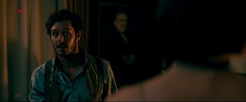 Movie still from “Ready or Not” (2019), directed by Matt Bettinelli-Olpin – A man standing in front of a painting of an old man; Medium shot, Over the shoulder angle