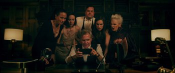 Movie still from “Ready or Not” (2019), directed by Matt Bettinelli-Olpin – A group of people standing around a man holding a cell phone; Medium shot, Overhead angle