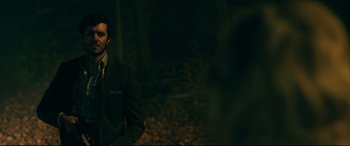 Movie still from “Ready or Not” (2019), directed by Matt Bettinelli-Olpin – A man in a suit standing in the woods; Medium shot, Over the shoulder angle