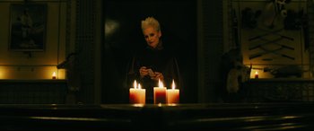 Movie still from “Ready or Not” (2019), directed by Matt Bettinelli-Olpin – A woman sitting in front of candles looking at her cell phone; Medium shot, Low angle