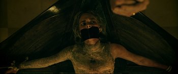 Movie still from “Ready or Not” (2019), directed by Matt Bettinelli-Olpin – A woman with her mouth taped shut is laying on the ground; Close Up shot, Overhead angle