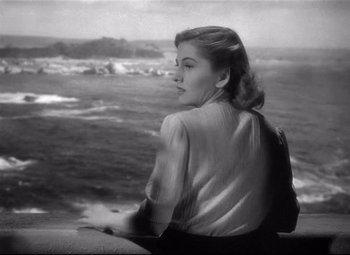 Movie still from “Rebecca” (1940), directed by Alfred Hitchcock – A black and white photo of a woman looking out at the ocean; Medium shot, High angle