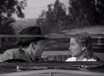 Movie still from “Rebecca” (1940), directed by Alfred Hitchcock – A man and a woman sitting in the back of a car; Medium shot, Over the shoulder angle