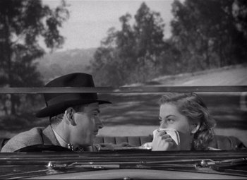 Movie still from “Rebecca” (1940), directed by Alfred Hitchcock – A man and a woman sitting in the back of a car; Medium shot, Over the shoulder angle