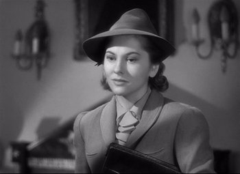 Movie still from “Rebecca” (1940), directed by Alfred Hitchcock – A woman in a suit and a hat holding a purse; Close Up shot, Low angle