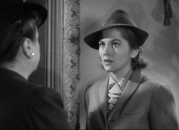 Movie still from “Rebecca” (1940), directed by Alfred Hitchcock – A woman in a suit and hat looking in the mirror; Close Up shot, Over the shoulder angle