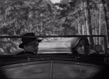 Movie still from “Rebecca” (1940), directed by Alfred Hitchcock – A man and a woman in the back seat of a car; Medium shot, High angle