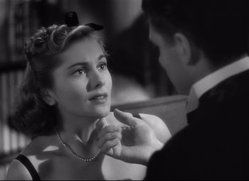 Movie still from “Rebecca” (1940), directed by Alfred Hitchcock – A woman sitting in front of a man in a suit; Close Up shot, Over the shoulder angle