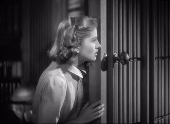 Movie still from “Rebecca” (1940), directed by Alfred Hitchcock – A woman standing in front of a wooden door; Close Up shot, High angle