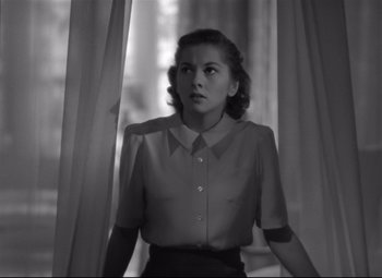 Movie still from “Rebecca” (1940), directed by Alfred Hitchcock – A black and white photo of a woman standing in front of a window; Medium shot, Low angle