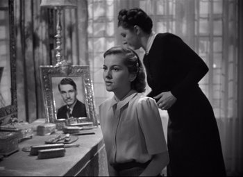Movie still from “Rebecca” (1940), directed by Alfred Hitchcock – A woman standing next to a man in front of a mirror; Medium shot, Low angle