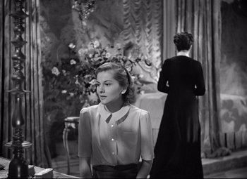 Movie still from “Rebecca” (1940), directed by Alfred Hitchcock – A woman standing in front of another woman in a room; Medium shot, Over the shoulder angle