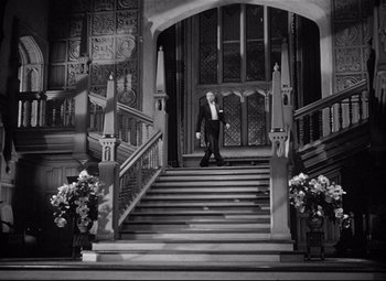 Movie still from “Rebecca” (1940), directed by Alfred Hitchcock – A black and white photo of a man walking down a set of stairs; Extreme Wide shot, Low angle