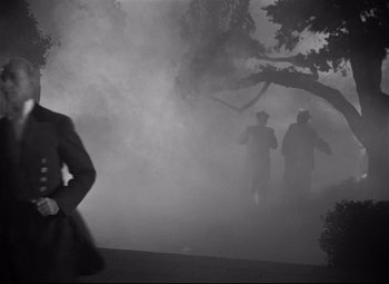 Movie still from “Rebecca” (1940), directed by Alfred Hitchcock – A group of men walking through a fog filled park; Wide shot, Low angle