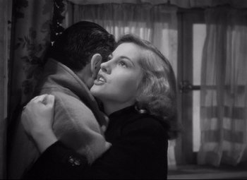 Movie still from “Rebecca” (1940), directed by Alfred Hitchcock – A man and a woman embracing each other in front of a window; Close Up shot, Over the shoulder angle