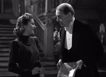 Movie still from “Rebecca” (1940), directed by Alfred Hitchcock – An old photo of a man and a woman talking to each other; Medium shot, Low angle