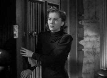 Movie still from “Rebecca” (1940), directed by Alfred Hitchcock – A black and white photo of a woman standing in front of a door; Close Up shot, High angle