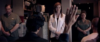 Movie still from “Hostage 911” (2018), directed by Robert Rodriguez – A woman standing in front of a man in a room; Medium shot, Over the shoulder angle