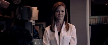 Movie still from “Hostage 911” (2018), directed by Robert Rodriguez – A woman wearing a lab coat standing in a room; Medium shot, Low angle