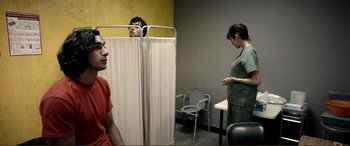 Movie still from “Hostage 911” (2018), directed by Robert Rodriguez – A woman standing in front of two men in an exam room; Medium shot, Over the shoulder angle