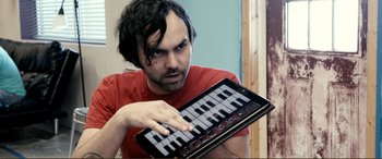 Movie still from “Hostage 911” (2018), directed by Robert Rodriguez – A man holding an electronic keyboard in his hands; Close Up shot, Overhead angle