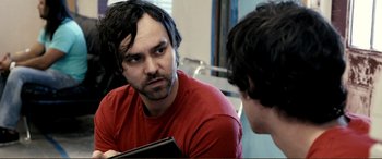 Movie still from “Hostage 911” (2018), directed by Robert Rodriguez – A man in a red t - shirt is looking at a man in a red shirt; Close Up shot, Over the shoulder angle