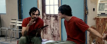 Movie still from “Hostage 911” (2018), directed by Robert Rodriguez – Two men sitting in front of each other looking at a tablet computer; Medium shot, Over the shoulder angle