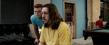 Movie still from “Hostage 911” (2018), directed by Robert Rodriguez – Two young men are sitting next to each other in a room; Medium shot, Over the shoulder angle