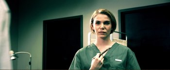 Movie still from “Hostage 911” (2018), directed by Robert Rodriguez – A woman in green scrubs holding a pair of scissors; Close Up shot, Over the shoulder angle