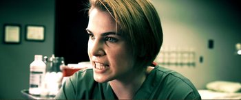 Movie still from “Hostage 911” (2018), directed by Robert Rodriguez – A person with short blonde hair; Close Up shot, Over the shoulder angle