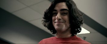 Movie still from “Hostage 911” (2018), directed by Robert Rodriguez – A man with long black hair wearing a red t - shirt; Close Up shot, Low angle