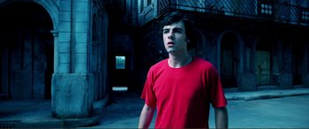 Movie still from “Hostage 911” (2018), directed by Robert Rodriguez – A man in a red shirt is standing in an alley; Medium shot, Low angle