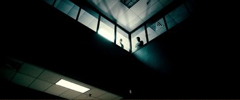 Movie still from “Hostage 911” (2018), directed by Robert Rodriguez – Two people are standing on a staircase looking out a window; Extreme Wide shot, Low angle