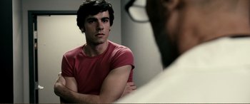 Movie still from “Hostage 911” (2018), directed by Robert Rodriguez – A man in a red t - shirt looks at himself in the mirror; Close Up shot, Over the shoulder angle