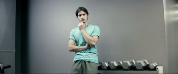 Movie still from “Hostage 911” (2018), directed by Robert Rodriguez – A young man standing in front of a row of barbells; Medium shot, Low angle