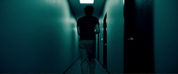 Movie still from “Hostage 911” (2018), directed by Robert Rodriguez – A man walking down a hallway in a dark room; Wide shot, Low angle