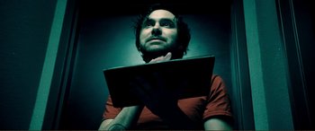 Movie still from “Hostage 911” (2018), directed by Robert Rodriguez – A man holding a computer in front of his face; Close Up shot, Overhead angle