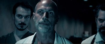 Movie still from “Hostage 911” (2018), directed by Robert Rodriguez – An old man with a beard and a headband; Close Up shot, Low angle